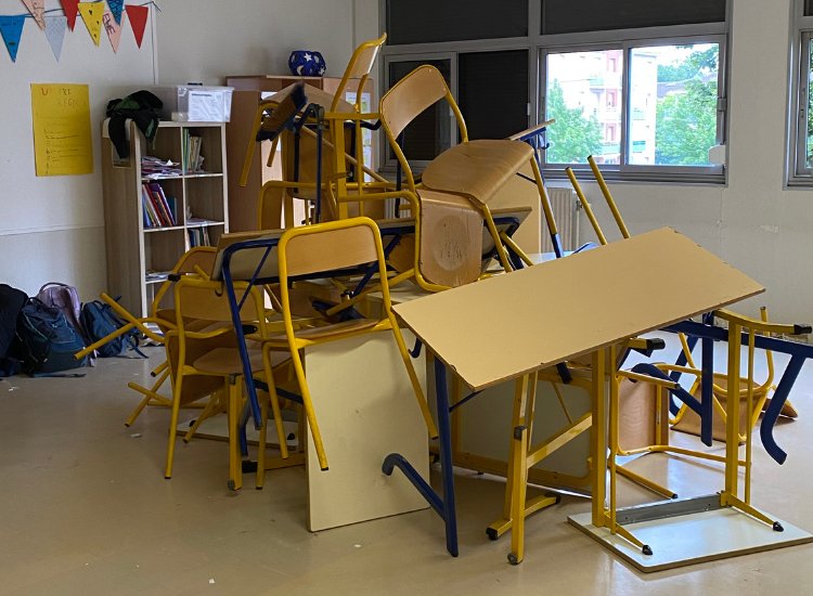 Klassenzimmer mit aufgetürmten Tischen und Stühlen