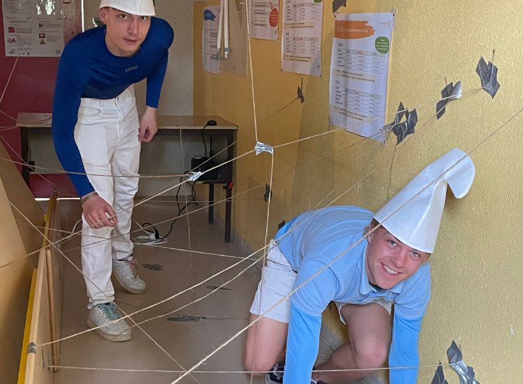 Schüler als Schlumpf verkleidet klettern durch befestigte Fäden