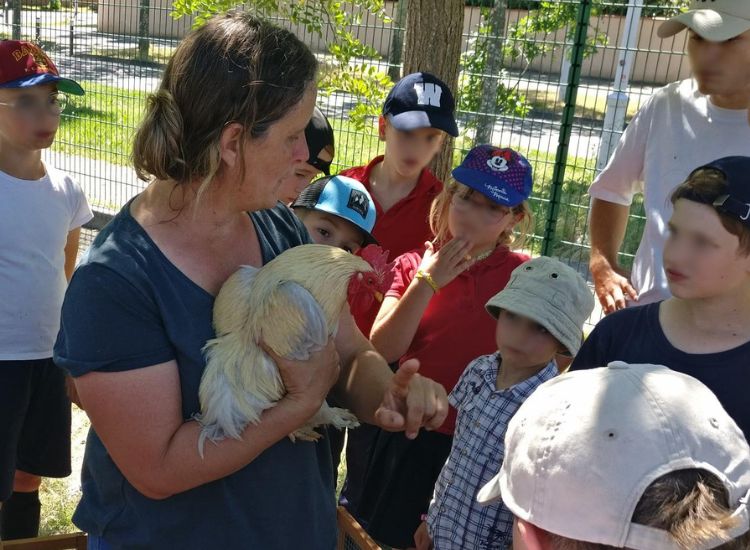 Deutsche Schule Toulouse: Kinder mit einer Erzieherin, die ein Huhn auf dem Arm hat