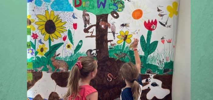 Deutsche Schule Toulouse : Kinder vor einem Infoplakat über Wiesen