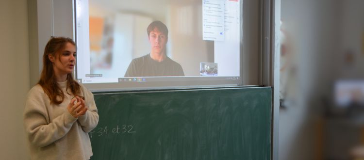 Studentin neben einer Leinwand, auf der ein Studen zu sehen ist