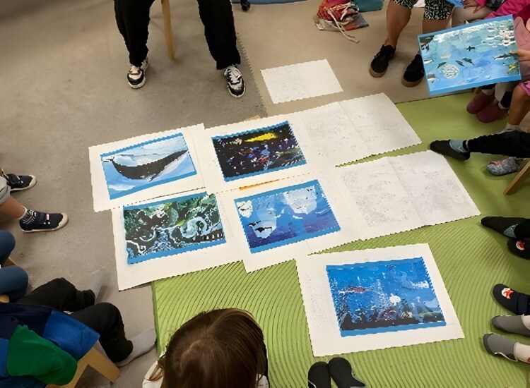 Sammlung von Bildern auf dem Boden, darum eine Gruppe von Kindern