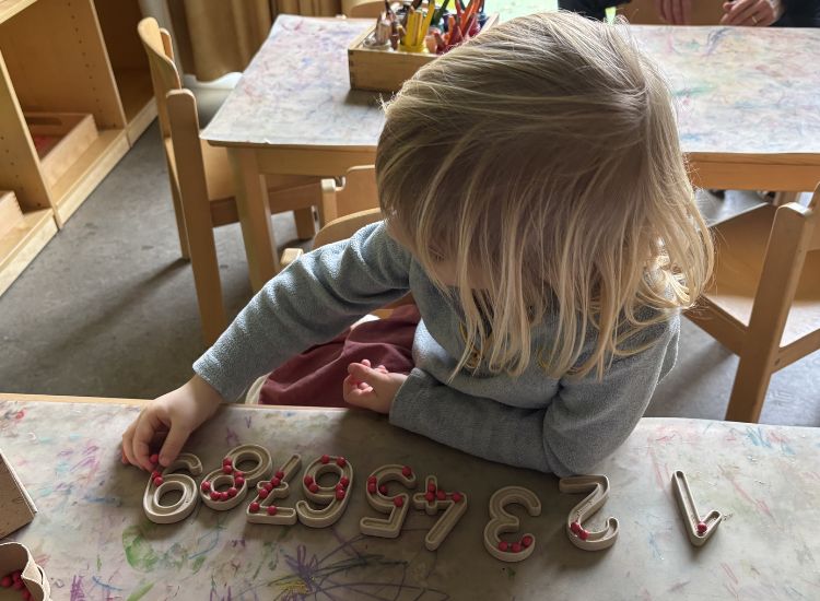 Kindergartenkind legt Kugeln in Zahlenformen