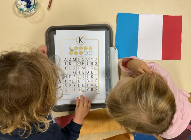 Kindergartenkinder suchen auf einem Arbeitsblatt den Buchstaben "K"