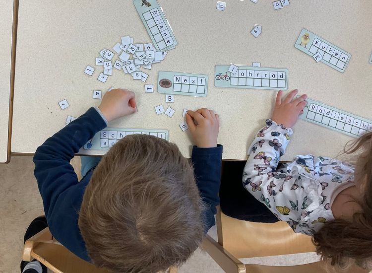 Kindergartenkinder legen Wörter mit Buchstabenkärtchen nach