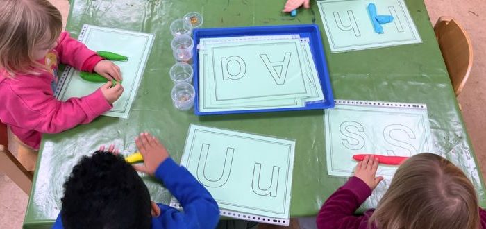 Kindergartenkinder bilden Buchstaben mit Knete nach