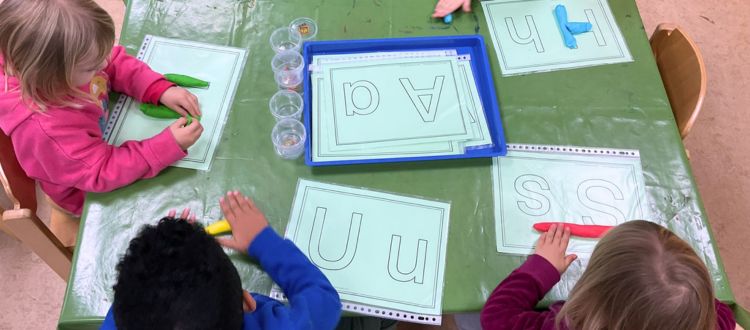 Kindergartenkinder bilden Buchstaben mit Knete nach