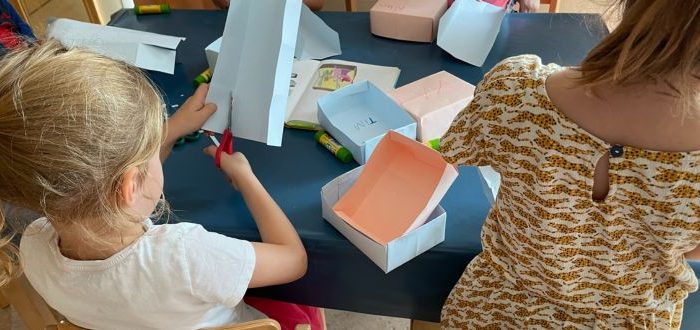 Zwei Mädchen basten Papierschachteln, Blick von hinten über die Schultern