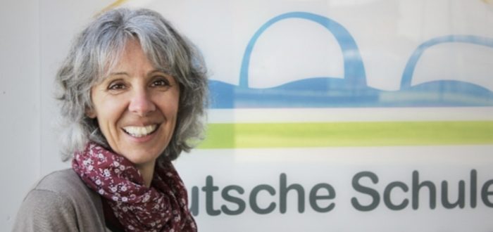 Portraitbild Dagmar Schröteler vor dem Logo der Deutschen Schule Toulouse