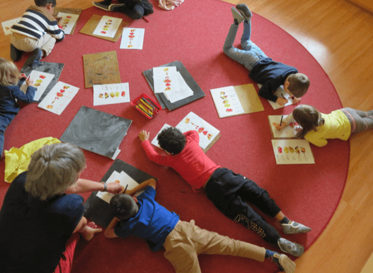 Kinder liegen auf dem Teppich und malen