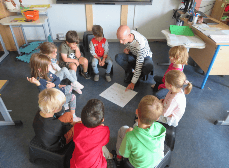 Vorschulkinder sitzen mit Lehrer im Kreis